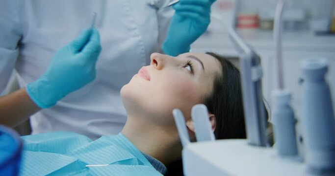 The dentist takes a medical instrument and examination oral cavity of a women