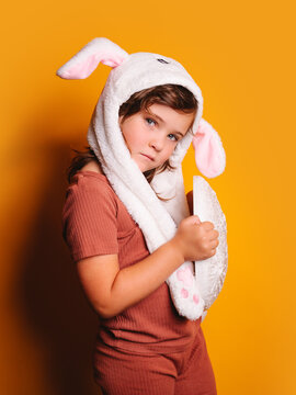 Shy girl in hat with bunny ears looking at camera