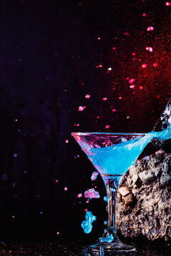 Glass of refreshing blue alcoholic cocktail in black studio
