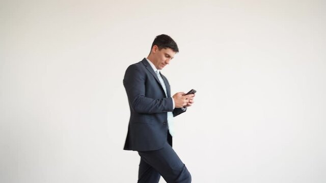 Businessman in a blue jacket and tie texting on the phone stumbles and falls. Man in business clothes walks and falls comically on his back. Funny bad luck situation on a white background.