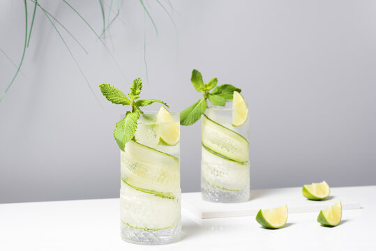 Refreshing cocktail with lime and cucumber served on white table