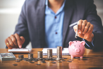 businessman holding a coin in a piggy bank On a table with sunlight. Money Saving Ideas for Financial Accounting