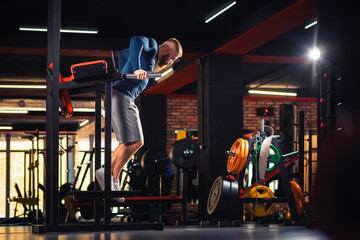 Athletic man trains in the gym with equipment. Copy space. Dips. The concept of fitness and wellness