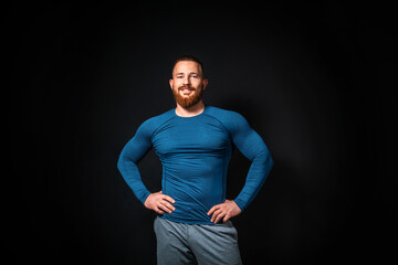 Athletic muscular smiling man posing on a black background. Copy space. Sports advertising concept
