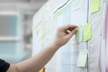 Commenting. Brainstorm or workshop. man's hand sticks a post-it note on the board.