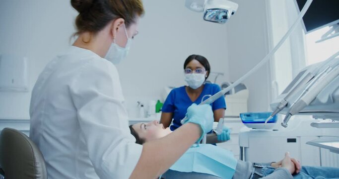 A dentist takes a machine for drilling teeth and starts treatment