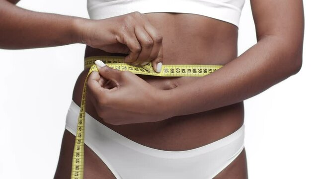 Weight loss and slimming concept. Unrecognizable african american lady model measuring her waist with tape