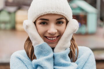 Young pretty smiling woman looking at the camera dressed knitted hat mittens. Cold weather, winter holidays, travel. New Year Christmas fair decorations, Valentines Day concept copy space
