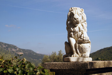 Fototapeta na wymiar Statue de lion sur muret avec paysage
