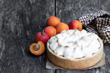 Tasty meringue pie with fresh apricot on wooden table