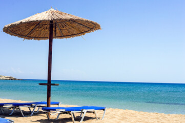 Two sun beds under sun umbrella at the beach. Zephyros beach. Greece