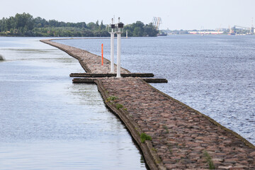 Brick pier with small lighthouse on river Daugava.