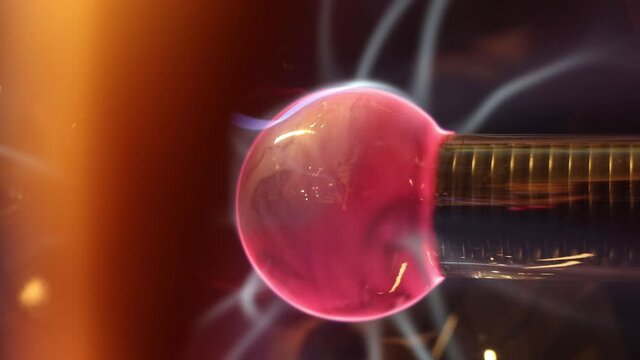 Plasma sphere with electric beam and strikes. Science education experiment with Tesla ball. Blue sparks and red nucleus in plasma ball with high energy and voltage.
