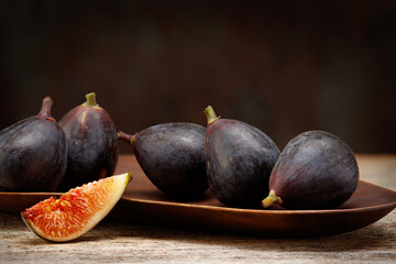 A few figs on a wooden plate. Ripe delicious fresh figs. Whole and sliced figs on rustic background. Selective focus