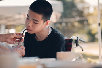 A young man with disabilities in wheelchair drink water by a parent-assisted, Caring for people with disabilities in daily activities.