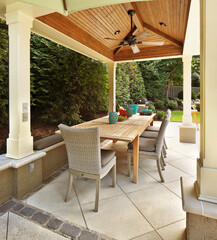 Table and chairs on outdoor covered patio with fan and lights