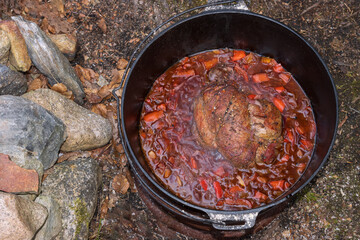 Top view of roast meat in an iron cast pot, dutch oven cooking