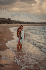 Fototapeta premium Two sisters playing on the shore of the sea at summer evening