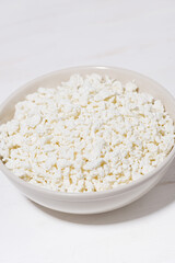 bowl of fresh farm cottage cheese on a white background, vertical closeup