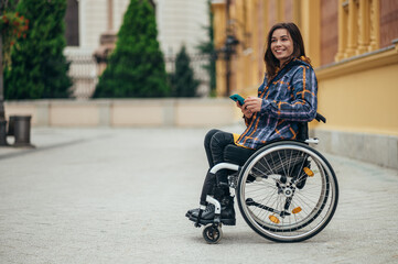 Woman in wheelchair using a smartphone while out in the city