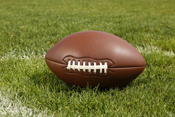 American football ball on green field grass outdoors