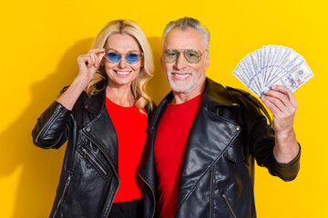 Portrait of pensioner beautiful handsome cheerful spouses holding cashback credit bank isolated over bright yellow color background