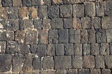 Wall of an ancient medieval Armenian church with carved crosses as background