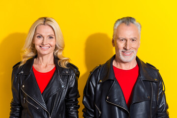 Portrait of two attractive cheerful fashionable grey-haired spouses isolated over bright yellow...