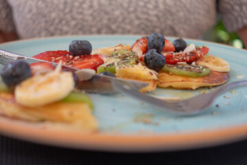 Close-up on plate and cutlery for healthy eating,  breakfast or break, classic american pancakes with banana, kiwi, strawberry and honey.