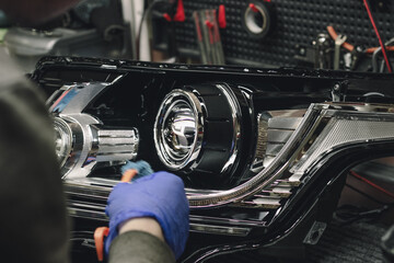 Car headlight in repair on the desktop close-up.An auto mechanic cleans the headlight lens after...