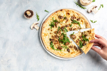 hand taking slices of pizza with mozzarella, mushrooms and arugula. Italian pizza. banner, menu, recipe place for text, top view