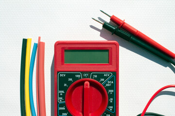 Multimeter with text on display and heat shrink insulation on white background