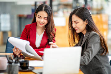 Two business Asian young women working together with laptop computer in the modern office.