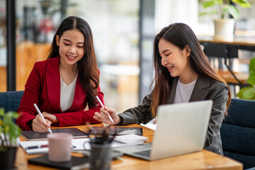 Two business Asian young women working together with laptop computer in the modern office.