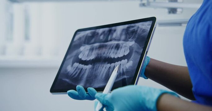 A dentist shows a patient a picture of teeth using a tablet