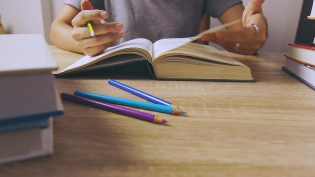 Close up and candid 4K of working woman who is reading a book concentratively on table with stacks of books as foreground shows concept of learning knowledge from self studying lifestyle. 