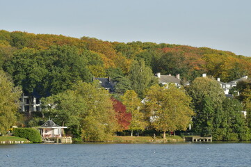 Obraz premium Le lac de Genval dans un cadre bucolique avec ses villas et immeubles à appartements dissimulés dans la nature luxuriante qui l'entoure en automne
