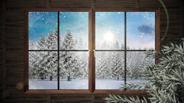 Wooden window frame and tree branch against snow falling over multiple trees on winter landscape