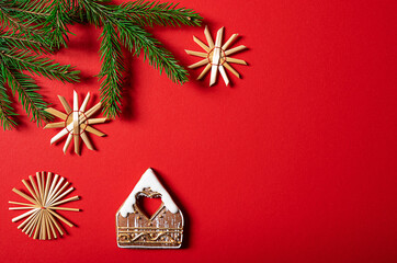 House-shaped cookie, decorations and fir tree branches on red background