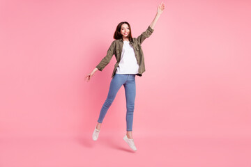 Full size photo of sweet short hairdo lady jump wear khaki shirt jeans sneakers isolated on pink color background