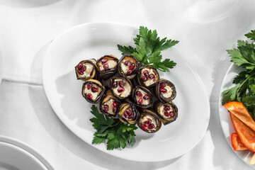 Fried eggplant slices stuffed with soft cheese and pomegranate on the table