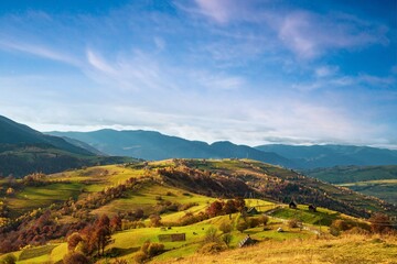 A path along the ridge of a hill with a large puddle and an old fence against the backdrop of a colorful forest