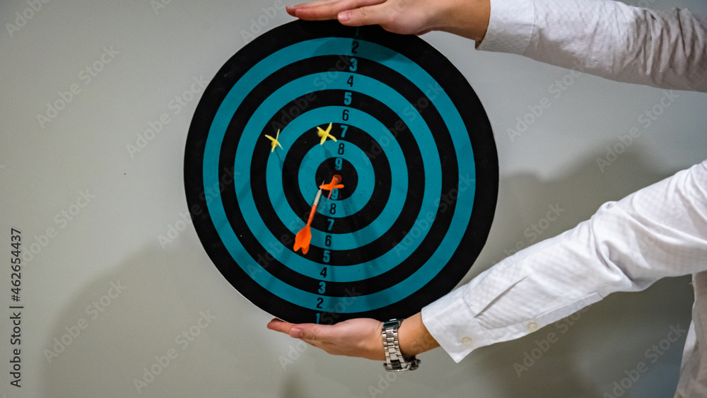 Poster close up shot of the dart arrow hit on bulleyes of dartboard to represent that the business reached 