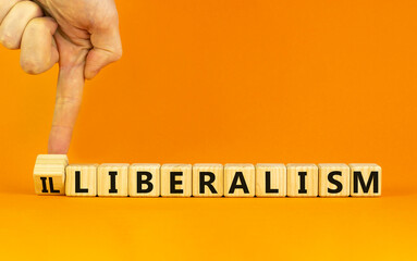 Illiberalism or liberalism symbol. Businessman turns a cube and changes the word 'illiberalism' to 'liberalism'. Beautiful orange background. Business, illiberalism or liberalism concept. Copy space.