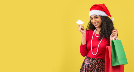 mujer afroamericana en fondo amarillo con bolsas de compras y una tarjeta de crédito