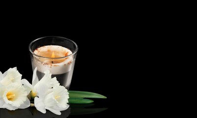WHITE FLOWER NEXT TO A LIGHTED CANDLE ON DARK BACKGROUND. DEATH, RELIGIOUS CEREMONY,