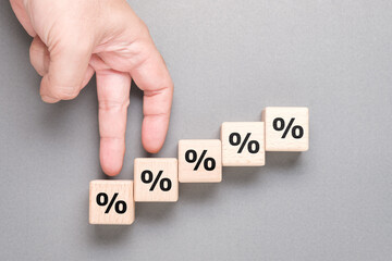 Closeup hand gesture as fingers walking step up on the wood cubes with percentage symbol, commission increase, insurance, and savings - obrazy, fototapety, plakaty
