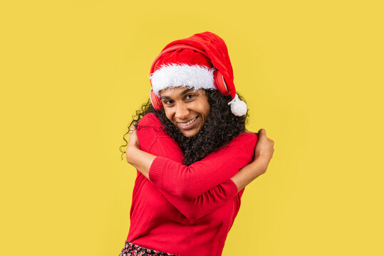 mujer vestida de navidad en fondo amarillo abrazando su cuerpo