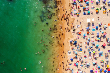 Fototapeta na wymiar Drone shot of many people enjoying the beach and the ocean in high season- vacation pattern.