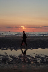 Fototapeta premium A vertical shot of a cheerful Caucasian lady from Spain enjoying sunset at the beach